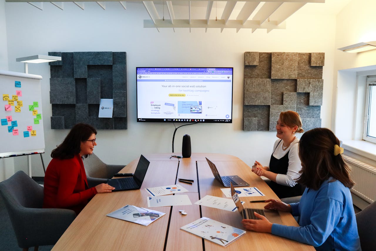 A team of women collaborating in a business meeting with laptops and presentations.