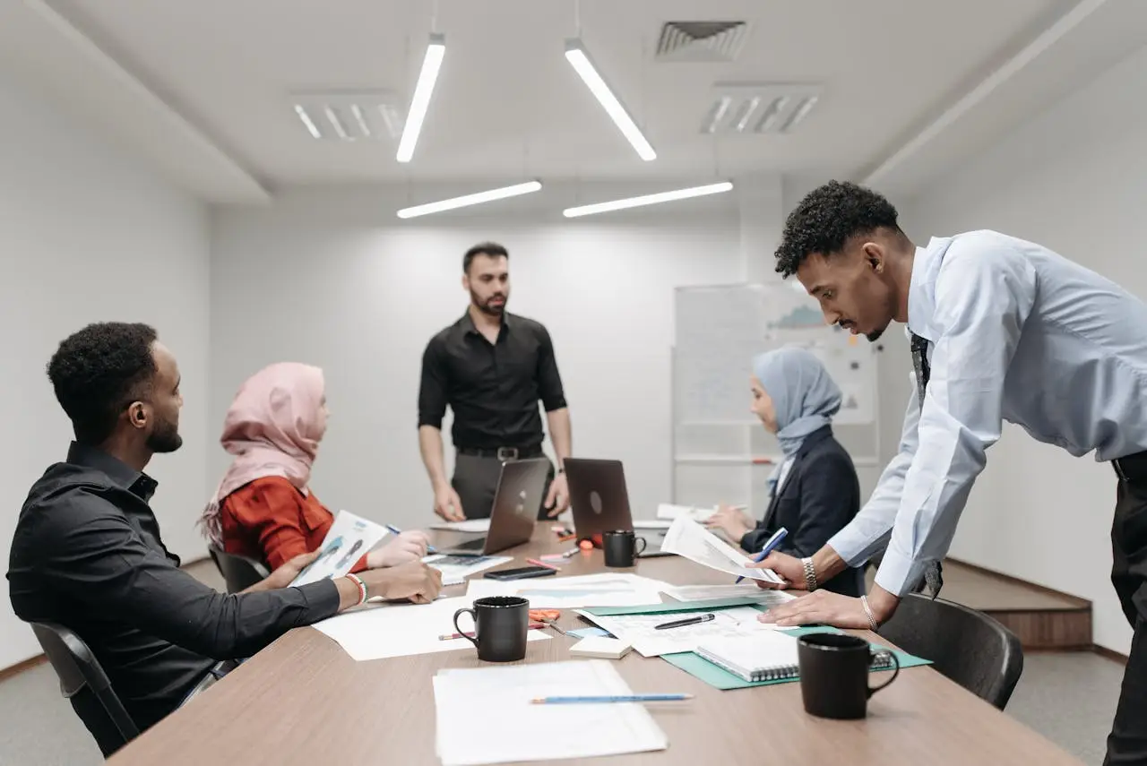 A diverse group of professionals in an office meeting discussing projects and ideas.