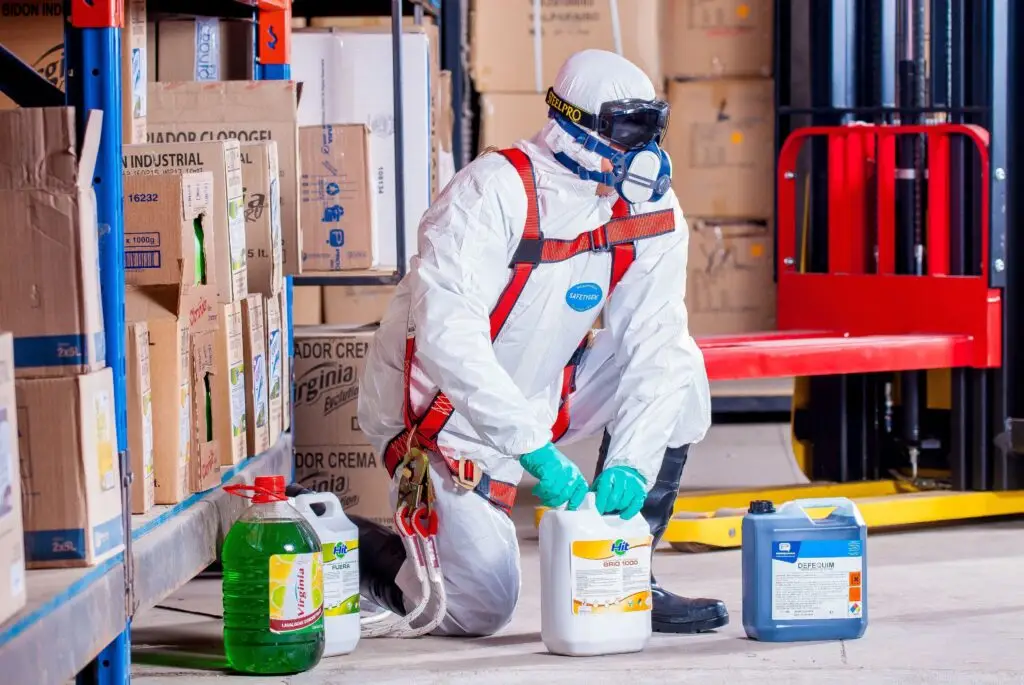 Training & Courses Industrial worker in protective gear handling chemicals in a warehouse environment.