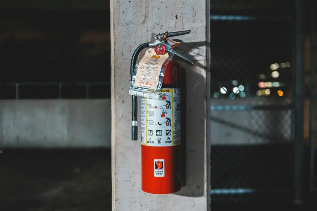 Training & Courses Extinguisher with instruction placed on shabby column near chain link on abandoned industrial zone